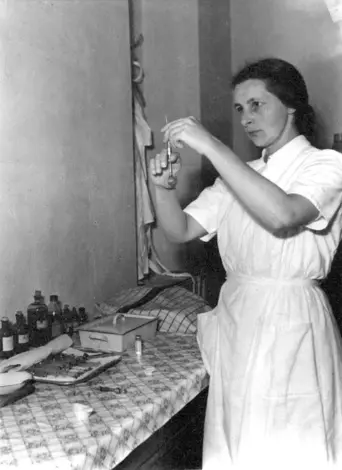 Diakonisse zieht eine Spritze auf. (Schwarz-Weiss-Foto)