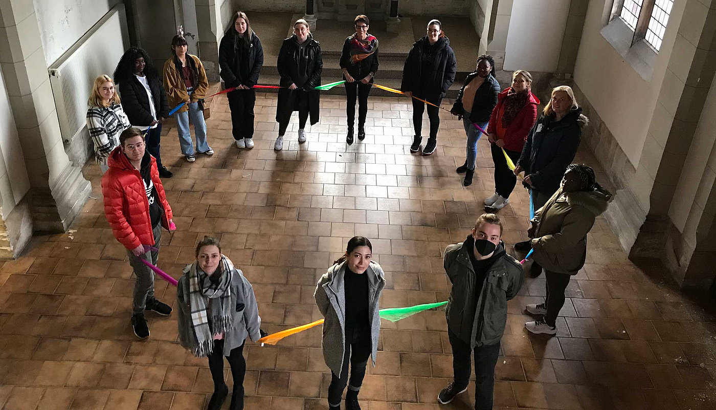 Menschen bilden mit bunten Tüchern einen Kreis im Zentrum Würde