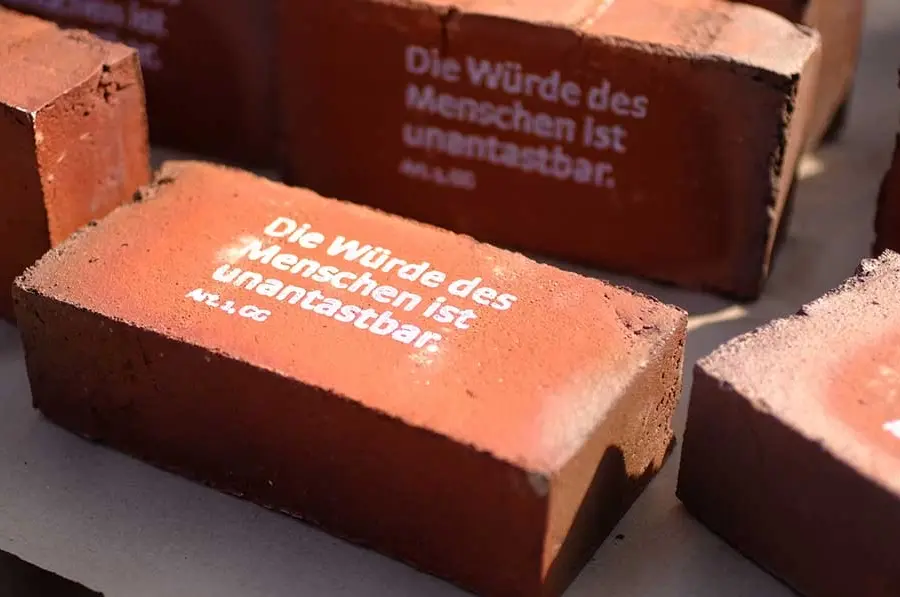 Rote Ziegelsteine mit Aufdruck: "Die Würde des Menschen ist unantastbar"