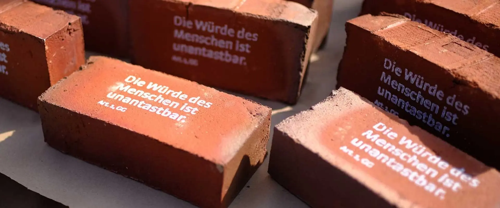 Rote Ziegelsteine mit Aufdruck: "Die Würde des Menschen ist unantastbar"